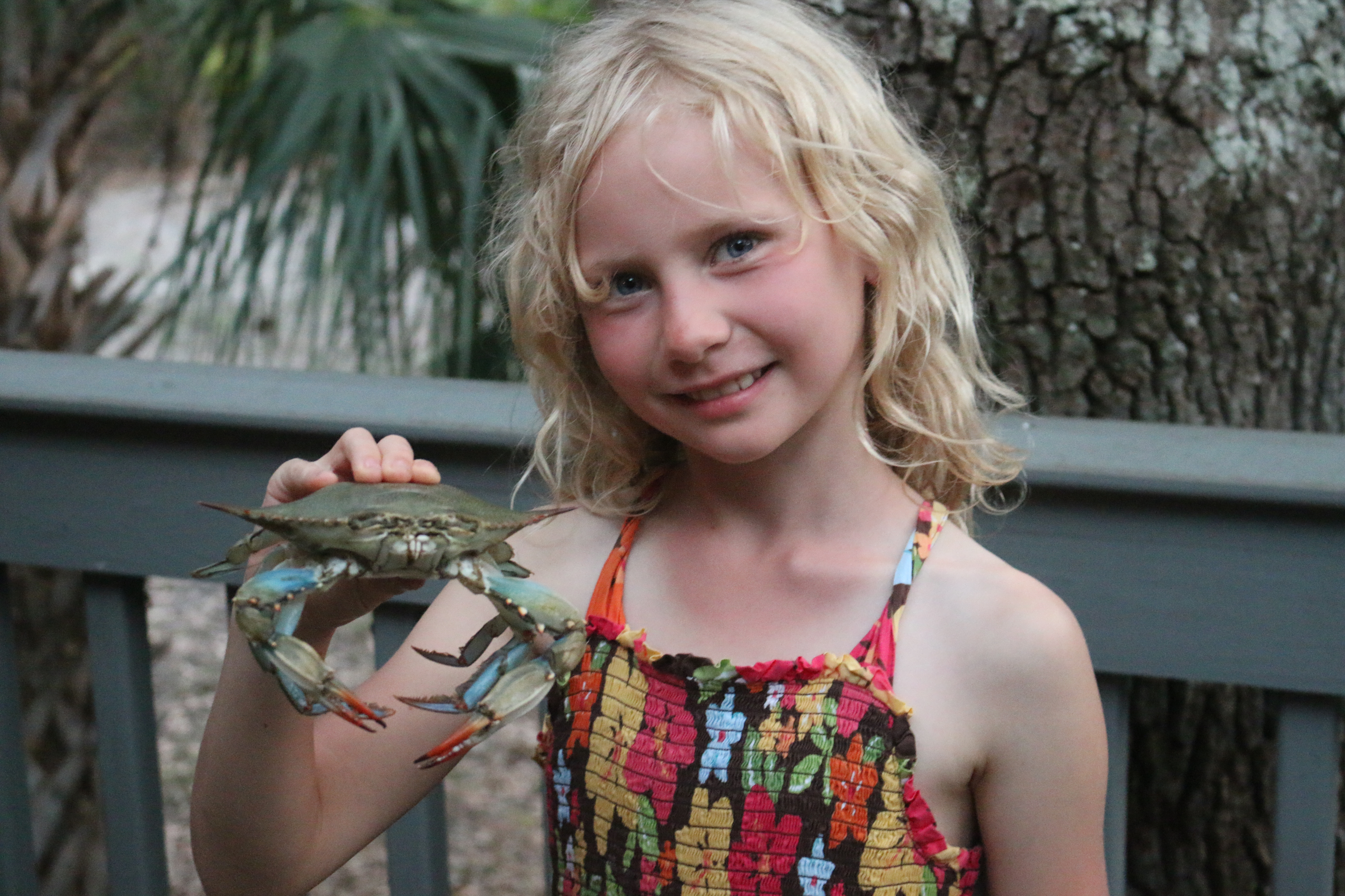 Smiling blonde child holding a blue crab