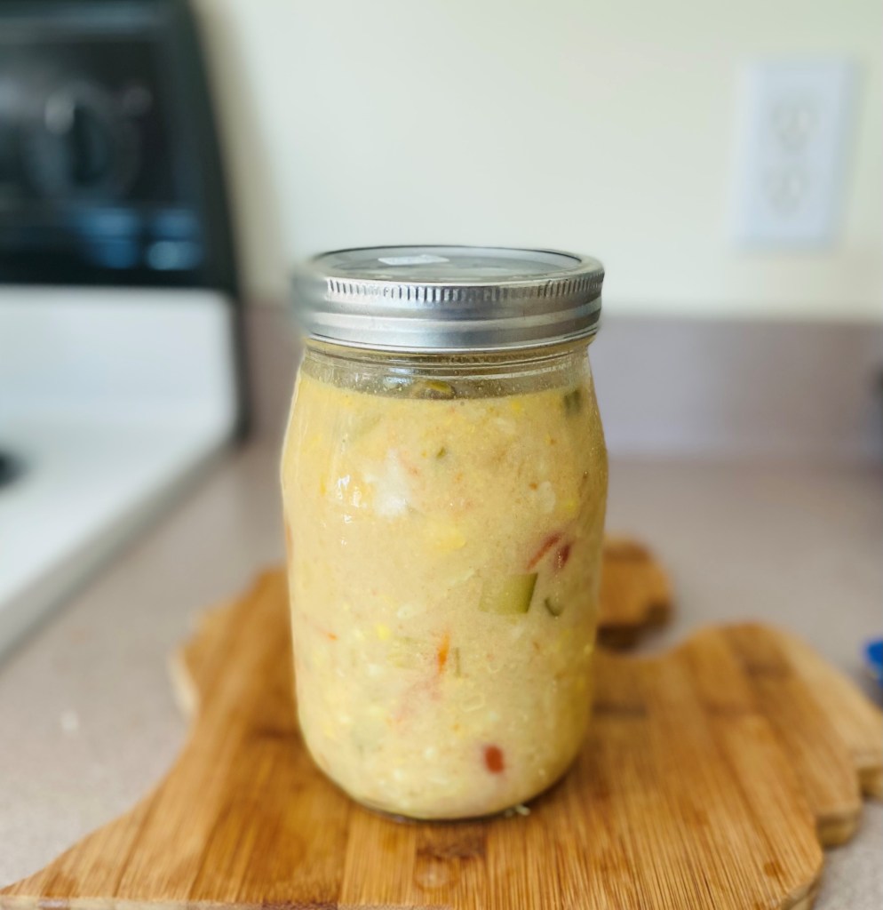 Photo by A. Rodríguez Cole. Leftover coconut curry with bluegill in a glass jar on top of cutting board shaped like Michigan’s lower peninsula.