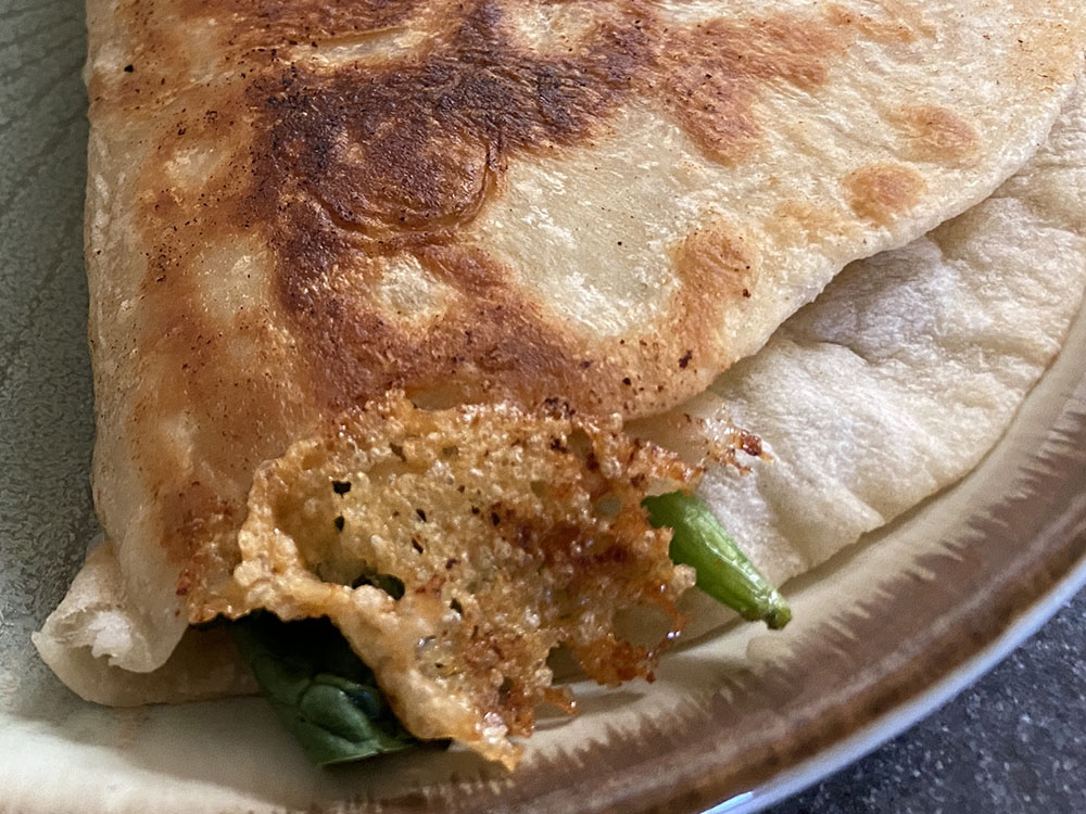 A bit of crispy cooked cheese stick invitingly to the edge of the tortilla.