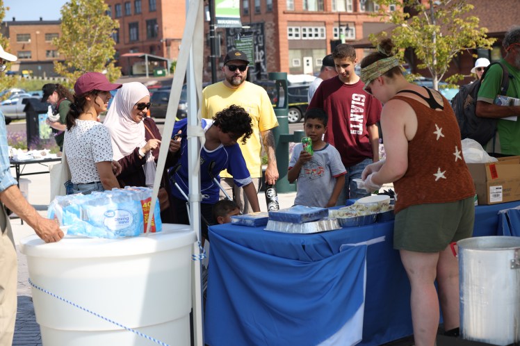 A group of people cluster around a table with samples of a seafood boil to enjoy